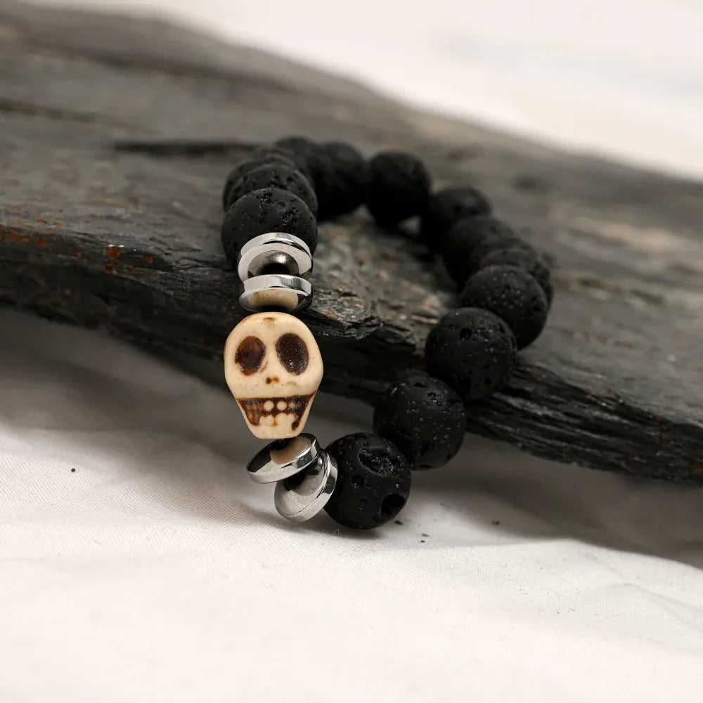 Side angle of gothic black lava stone bracelet with silver skull centerpiece and spacers