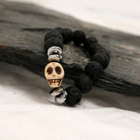 Side angle of gothic black lava stone bracelet with silver skull centerpiece and spacers