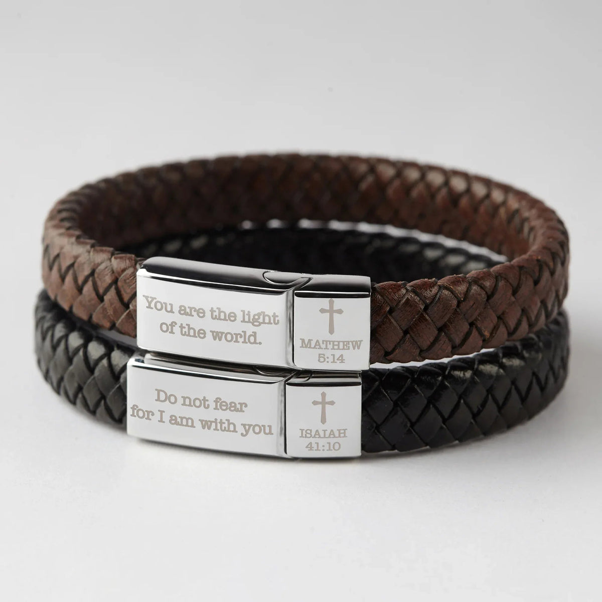 Christian bracelet worn on wrist featuring woven leather band and personalized Bible quote on metal plate.