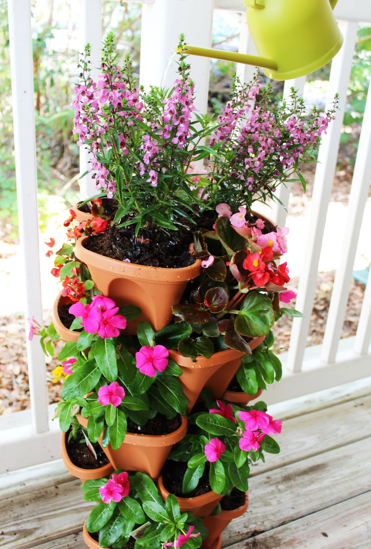 Stacked planters arranged outdoors, holding lush green herbs and small flowers in each tier.