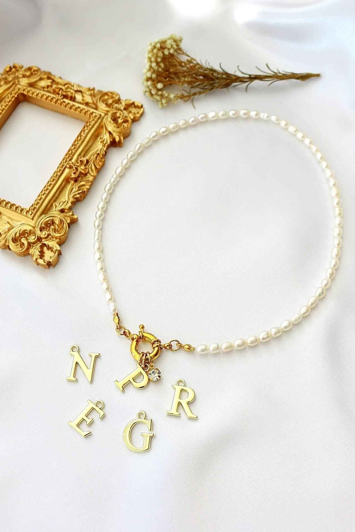 Freshwater pearl choker with gold-plated initial charm and front opening, presented on a neutral background.