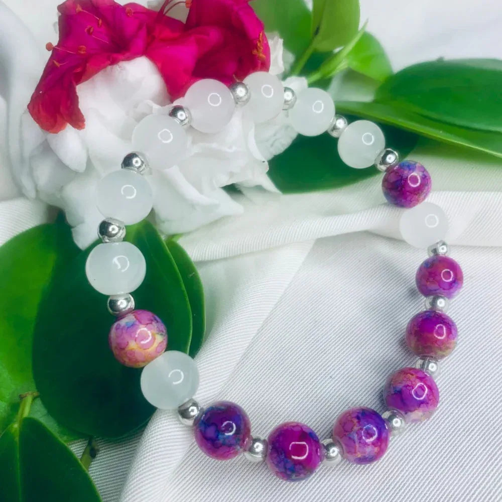 Close-up of white and purple stone beads with silver spacers on a stretch bracelet.
