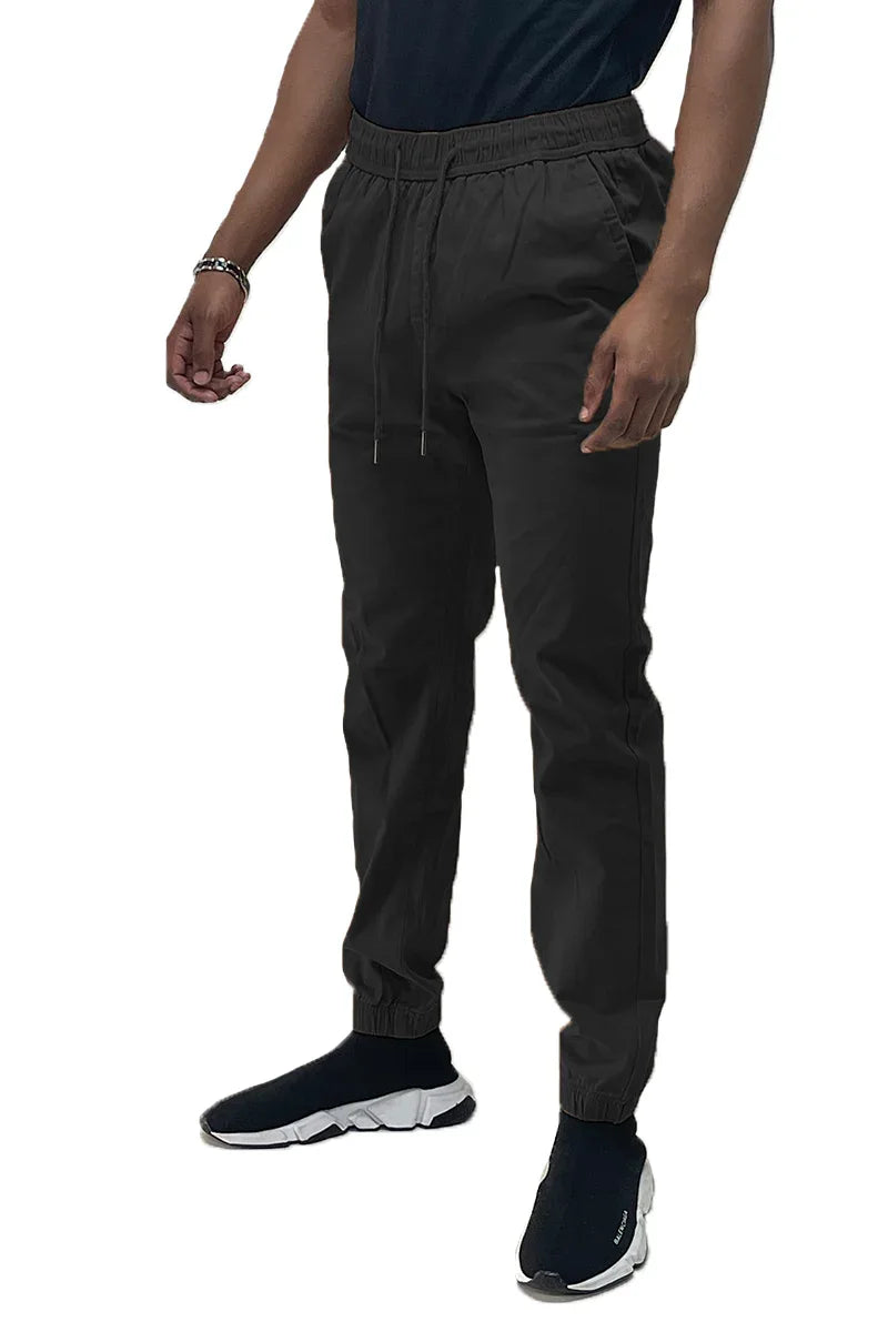 Close-up of black jogger pants fabric texture showing elastic waistband and side pocket.
