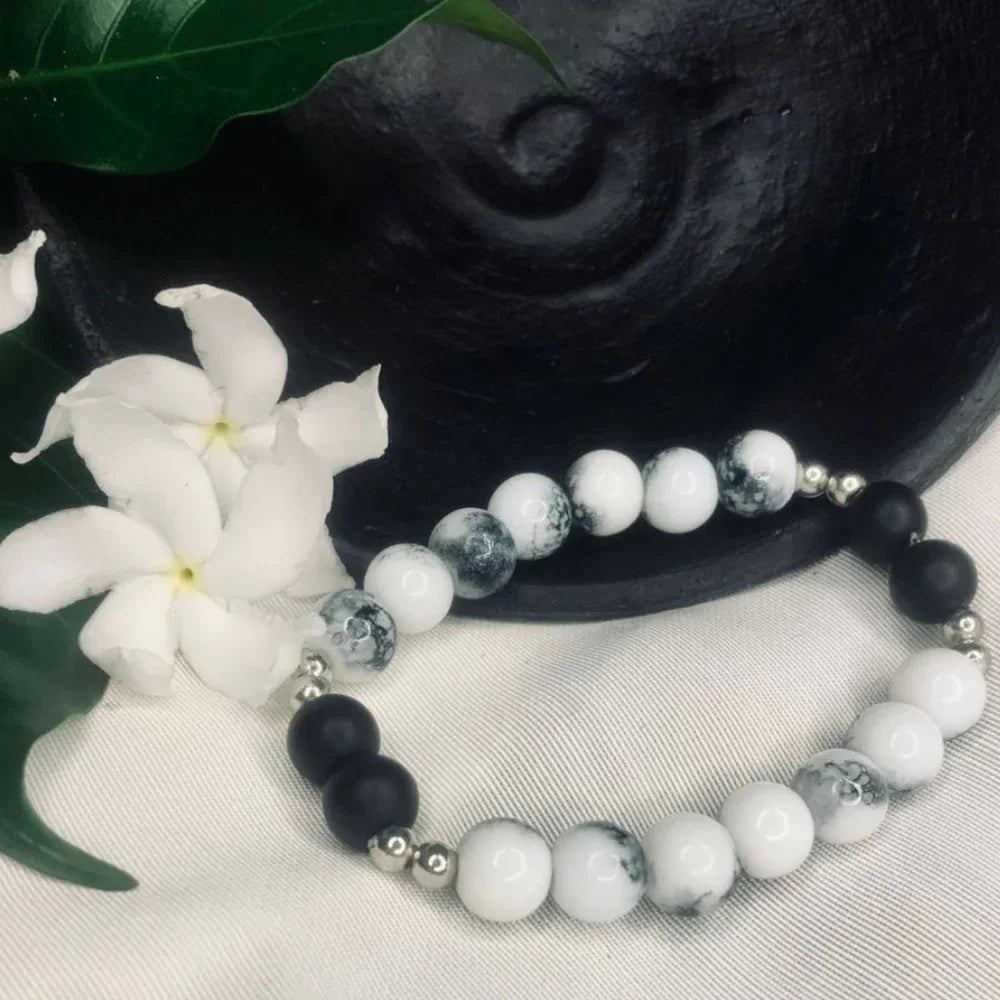 Detailed view of black onyx and howlite beads with shiny silver spacers forming a stretchy bracelet.