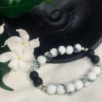 Detailed view of black onyx and howlite beads with shiny silver spacers forming a stretchy bracelet.