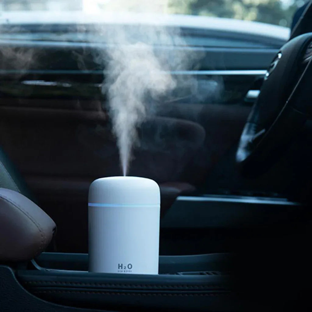 White USB-powered mini air humidifier with colorful LED night light glowing in dark room.