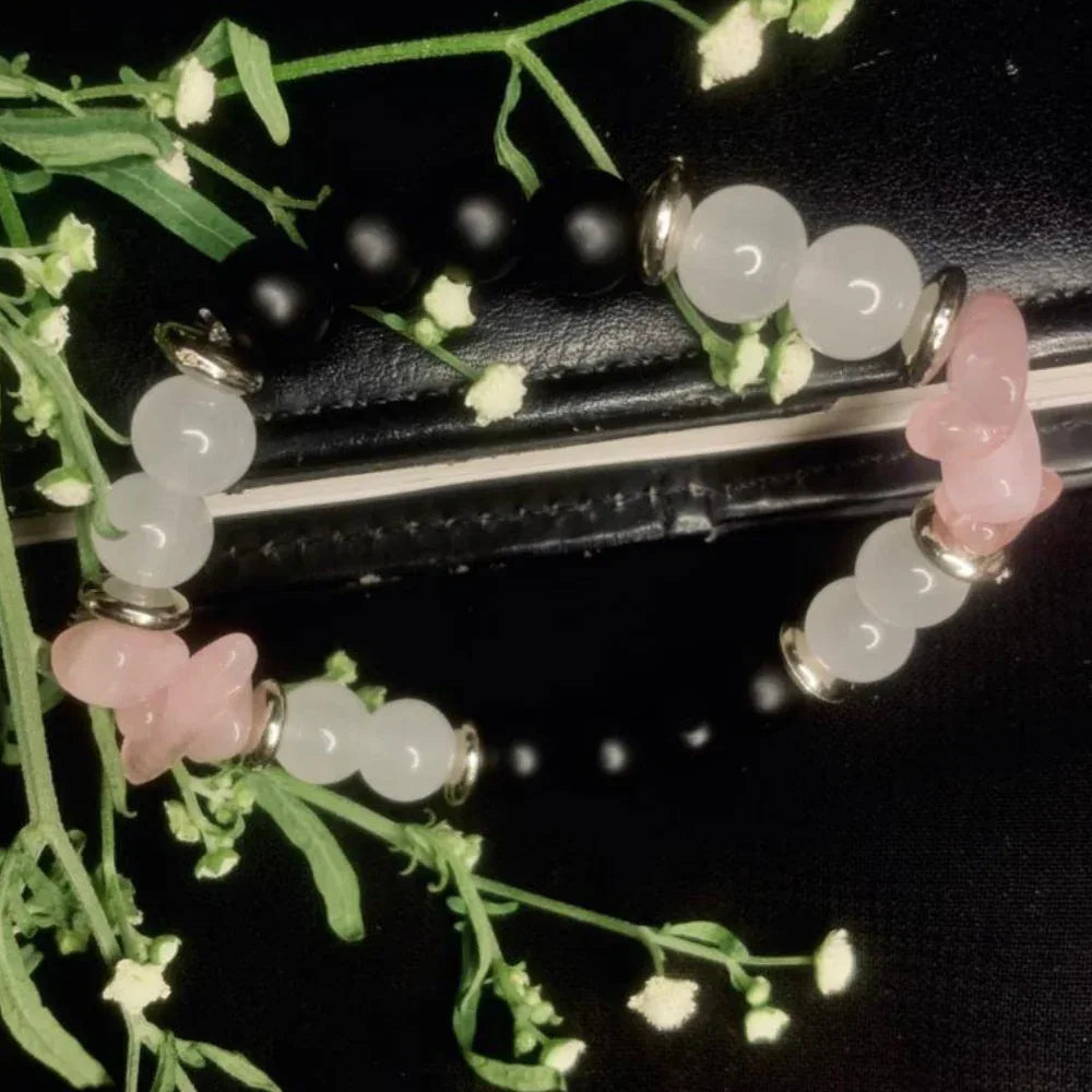 Hand wearing stretch bracelet featuring black onyx, white jade, rose quartz beads, and silver accents