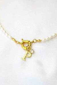 A freshwater pearl choker with a gold-plated initial charm, featuring a front opening and elegant white pearls.