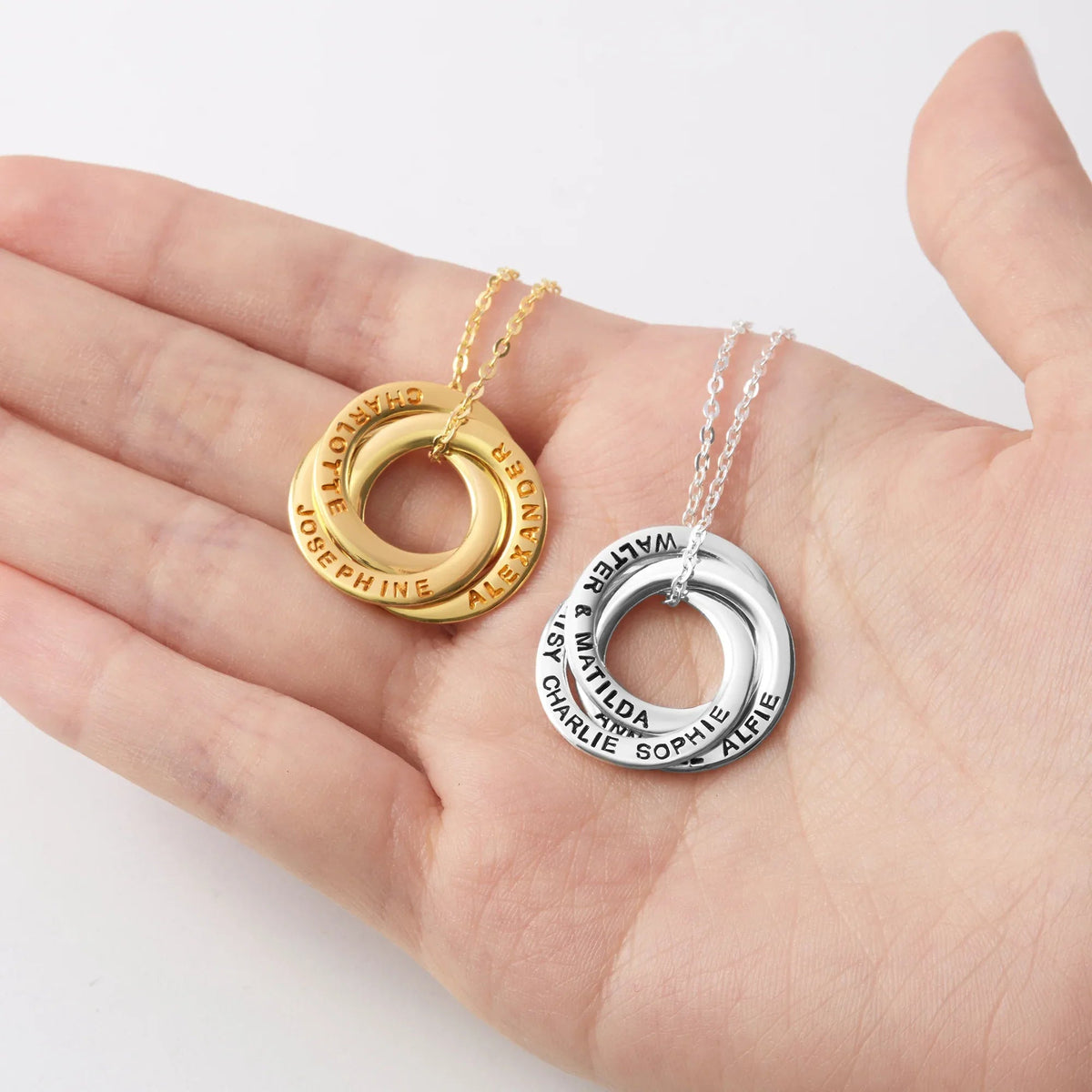 Silver layered interlocking rings necklace arranged artistically on a dark fabric background.