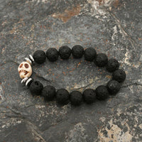 Close detail of silver skull bead surrounded by textured black lava stone beads on bracelet