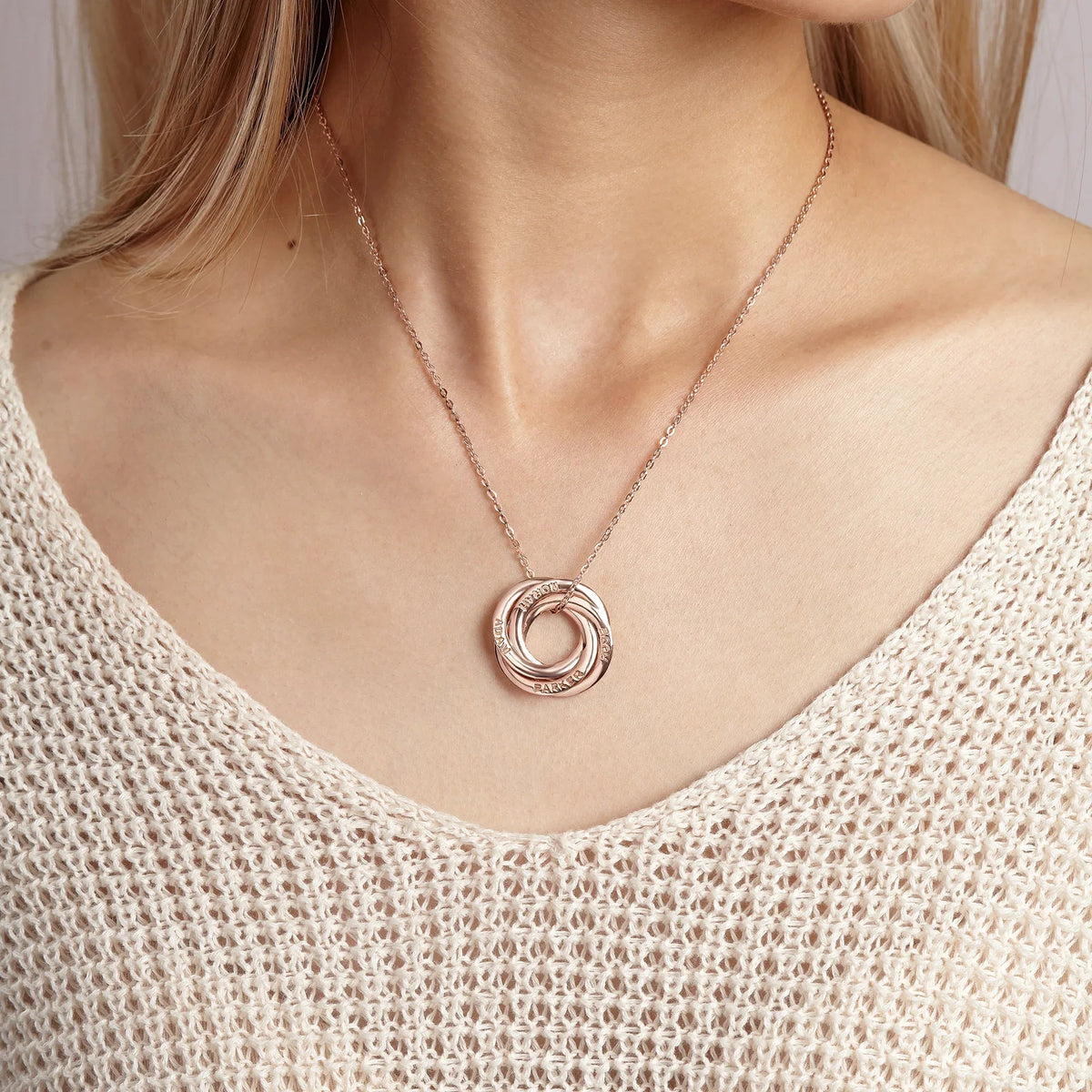 Stacked silver loop rings necklace worn on a person's neck, highlighting the personalized name engraving.