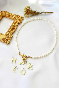 Freshwater pearl choker with gold-plated initial charm and front opening, presented on a neutral background.