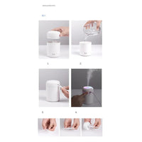 Small portable aroma diffuser connected via USB cable on office desk with laptop nearby.