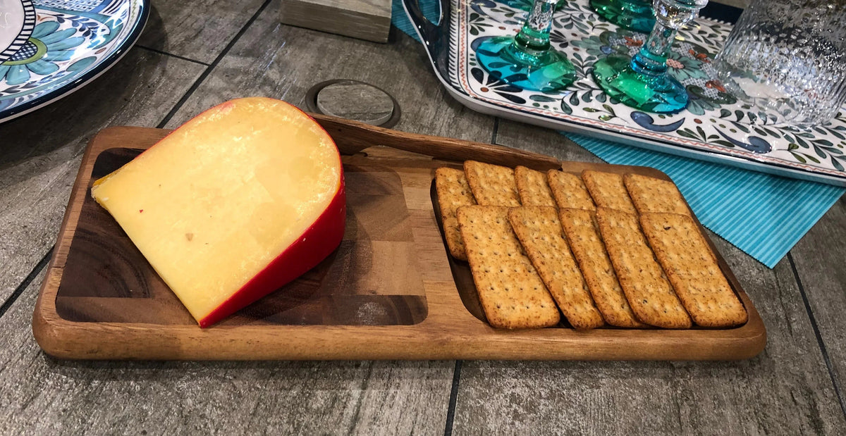 Elegant cheeseboard displaying assorted cheeses and crackers on rich end grain wood surface.