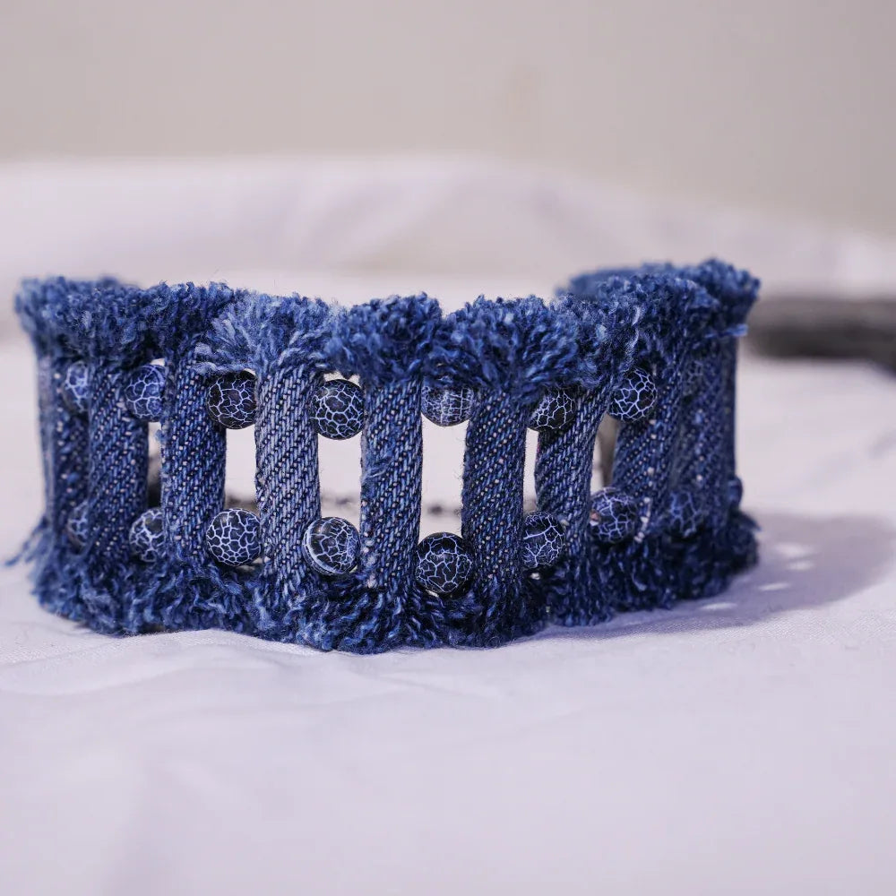 Close-up of denim tribal bracelet with lava and agate stones showing detailed stitching and texture.