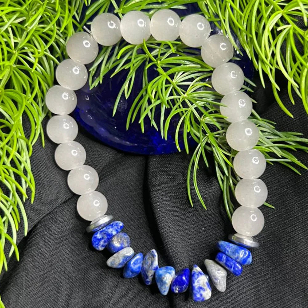 Close-up of bracelet with smooth white stone beads and irregular blue stone chips on white background.