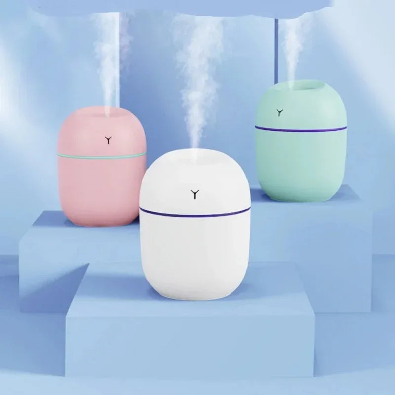 Close-up of white ultrasonic humidifier with USB cable connected, placed on wooden surface.