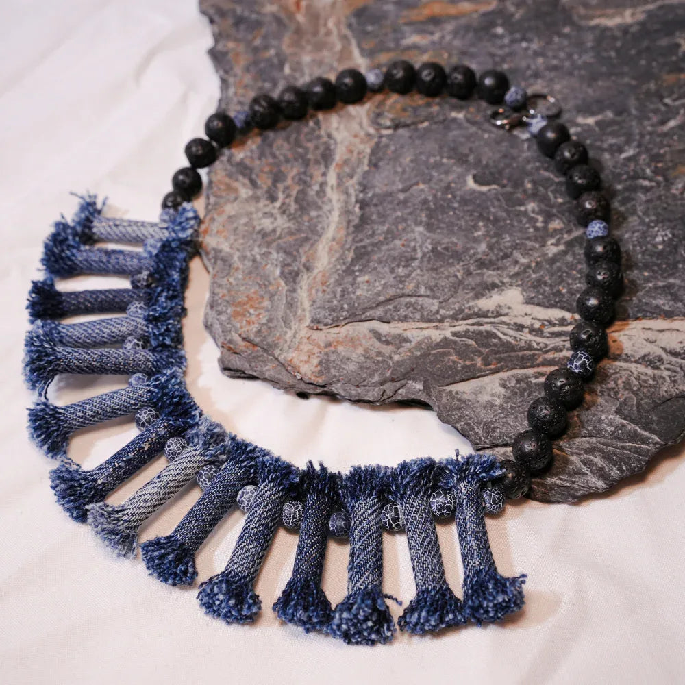 Denim necklace and tribal bracelet set featuring black lava and weathered agate stones on light background.