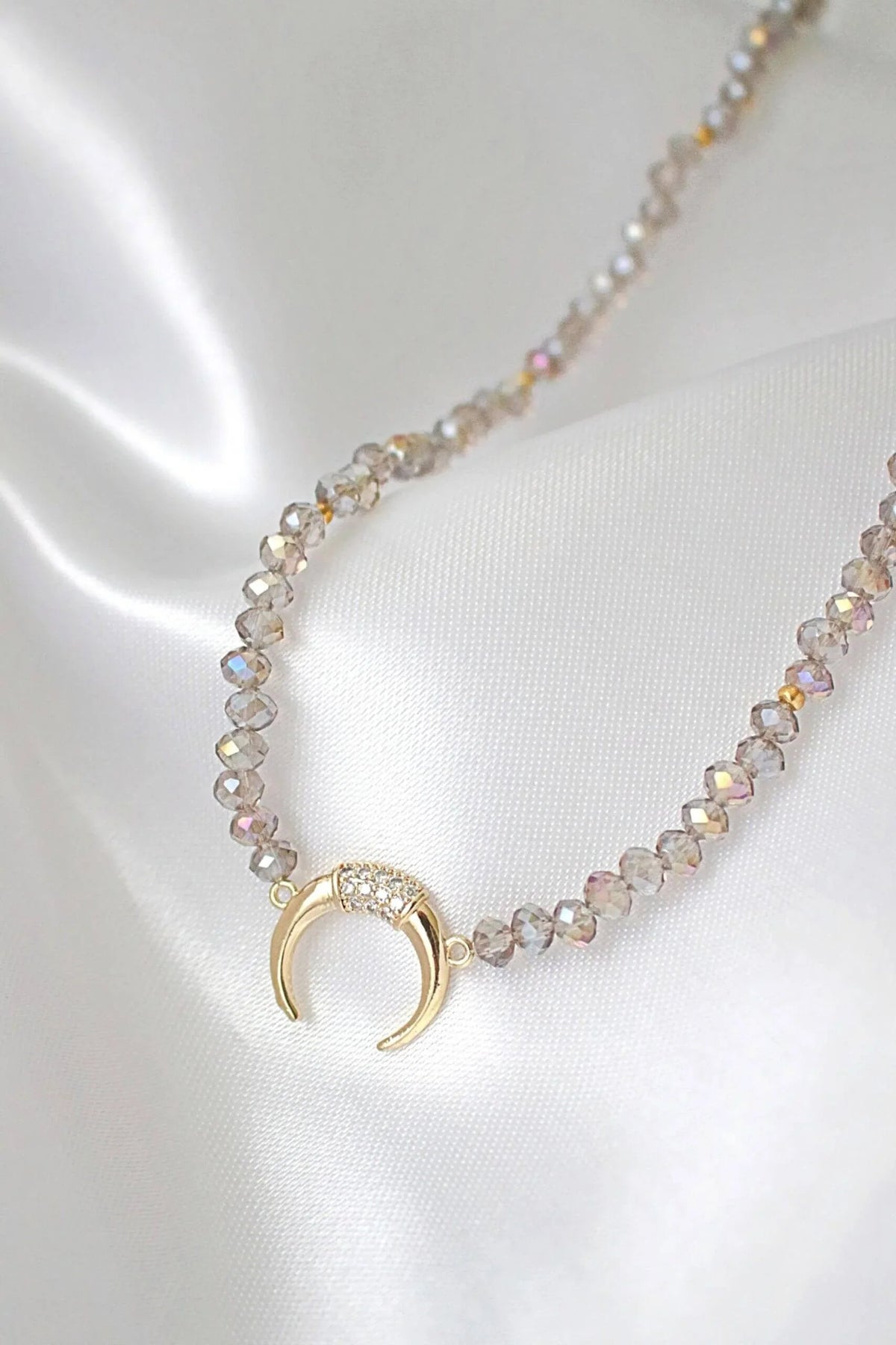 Light blue chrome Austrian crystal choker necklace laid flat highlighting crystals and gold charm pendant.