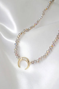 Light blue chrome Austrian crystal choker necklace laid flat highlighting crystals and gold charm pendant.