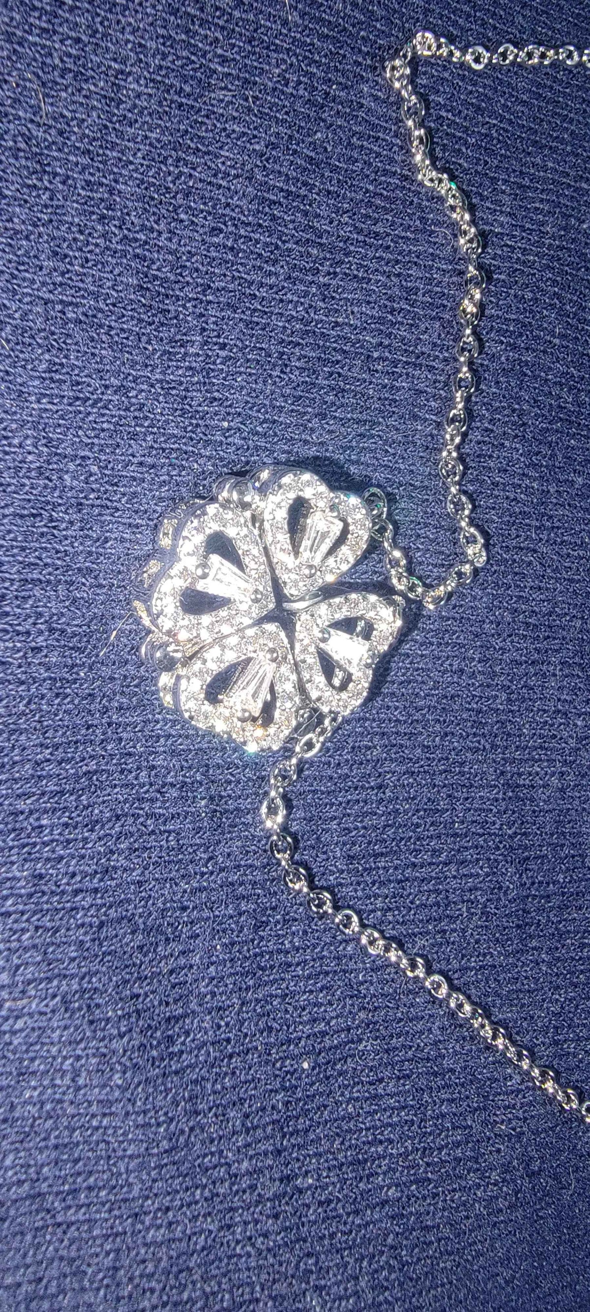 Elegant necklace pendant combining a four-leaf clover and heart shape in shiny silver metal.