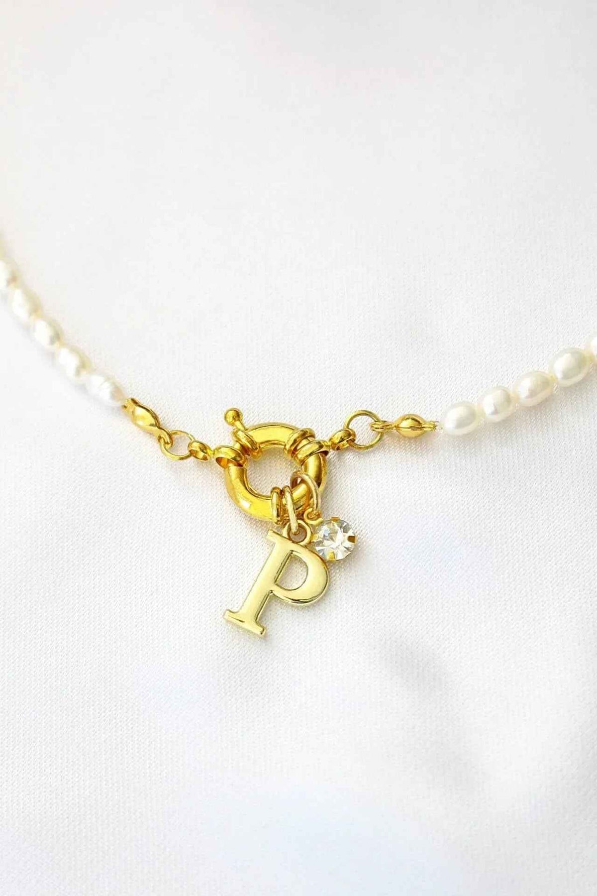 A freshwater pearl choker with a gold-plated initial charm, featuring a front opening and elegant white pearls.