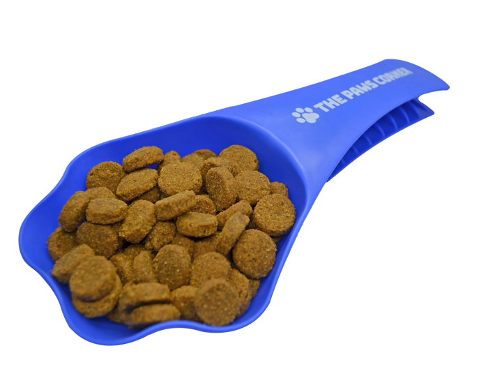 Paw-shaped green pet food scoop with handle and clip, holding 1 cup of dry kibble on a white background.
