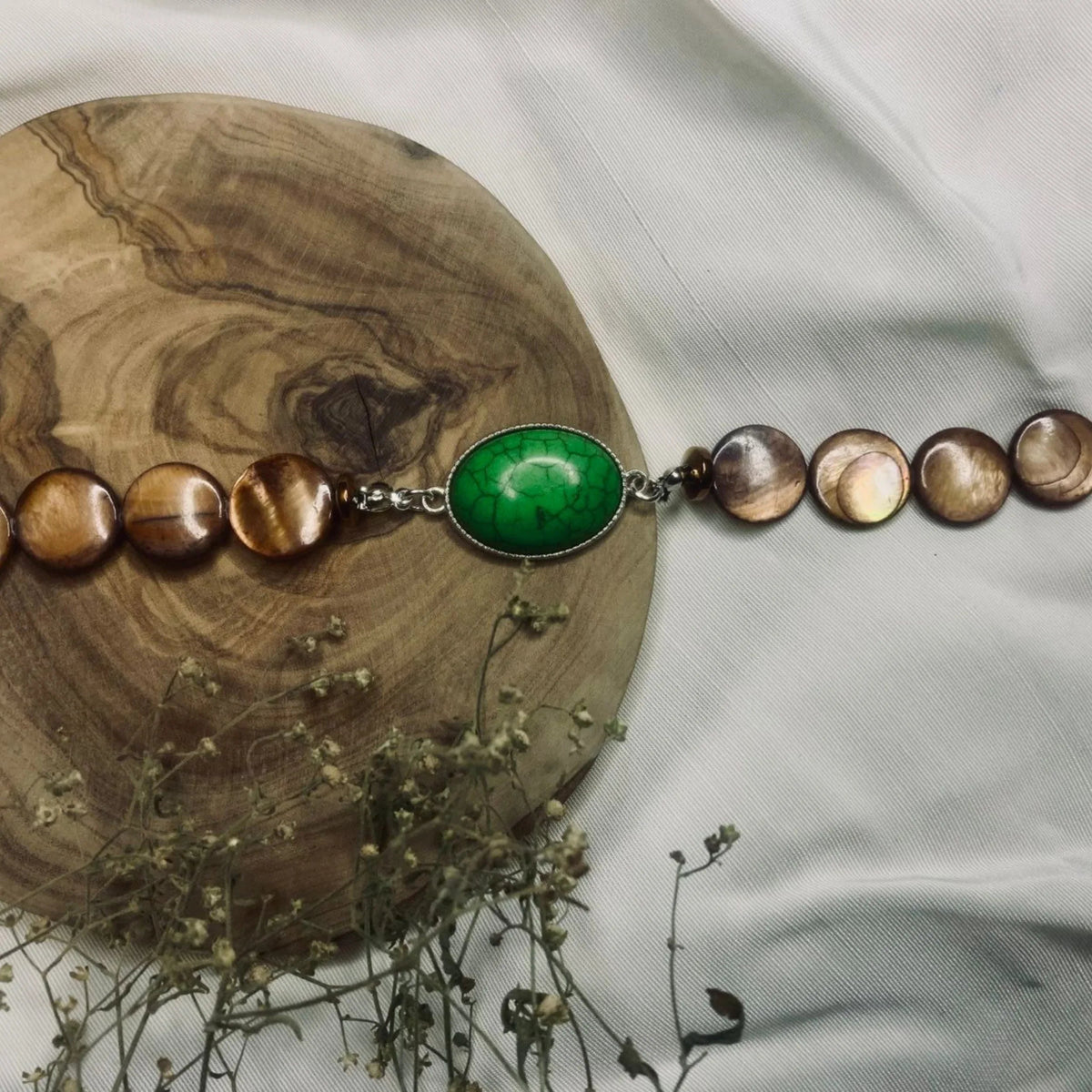Handcrafted natural stone bracelet resting on a light surface showing texture and color.