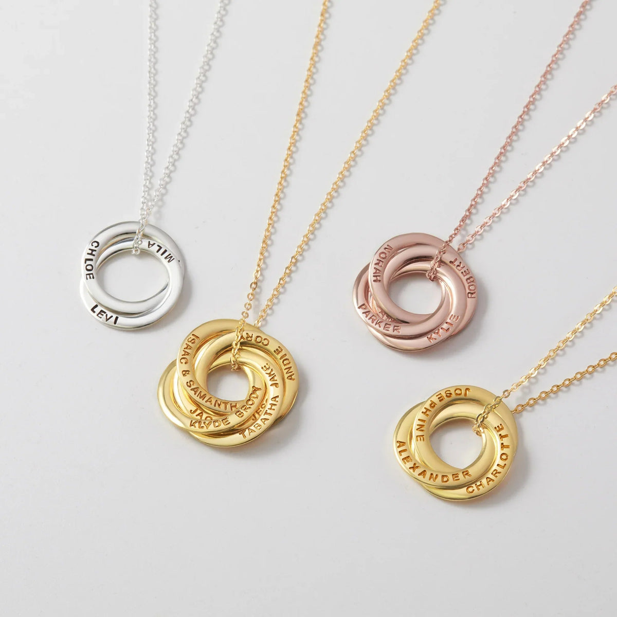 Close-up of three silver interlocking rings pendant on a delicate chain with engraved names.