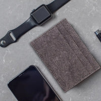 Close-up of dark grey coconut leather card holder showing textured surface and stitching.