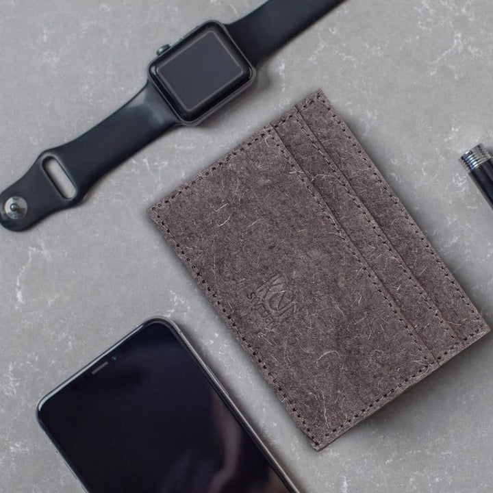 Close-up of dark grey coconut leather card holder showing textured surface and stitching.