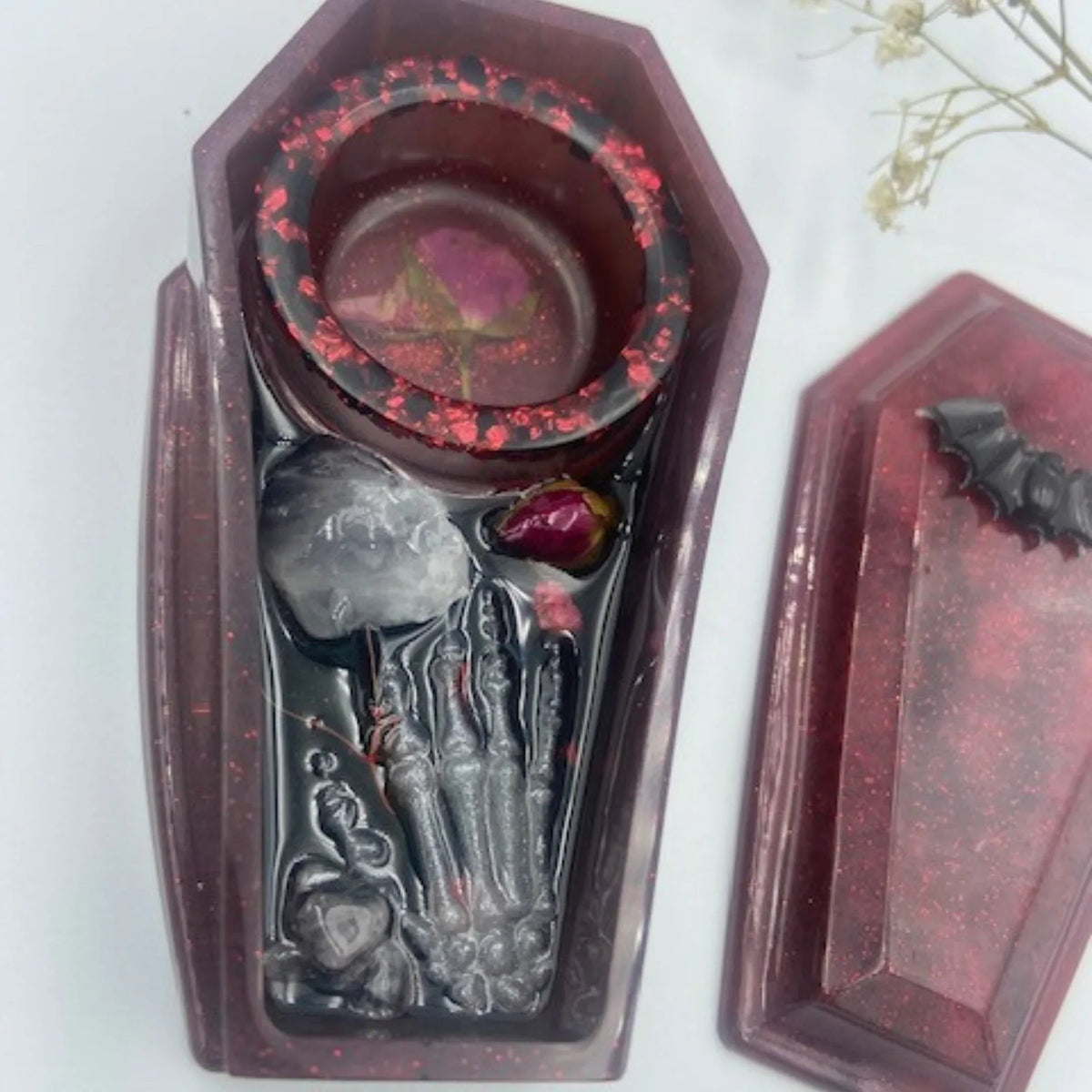 Close-up of spooky coffin tealight holder decorated with purple amethyst and a resin skeleton hand detail.
