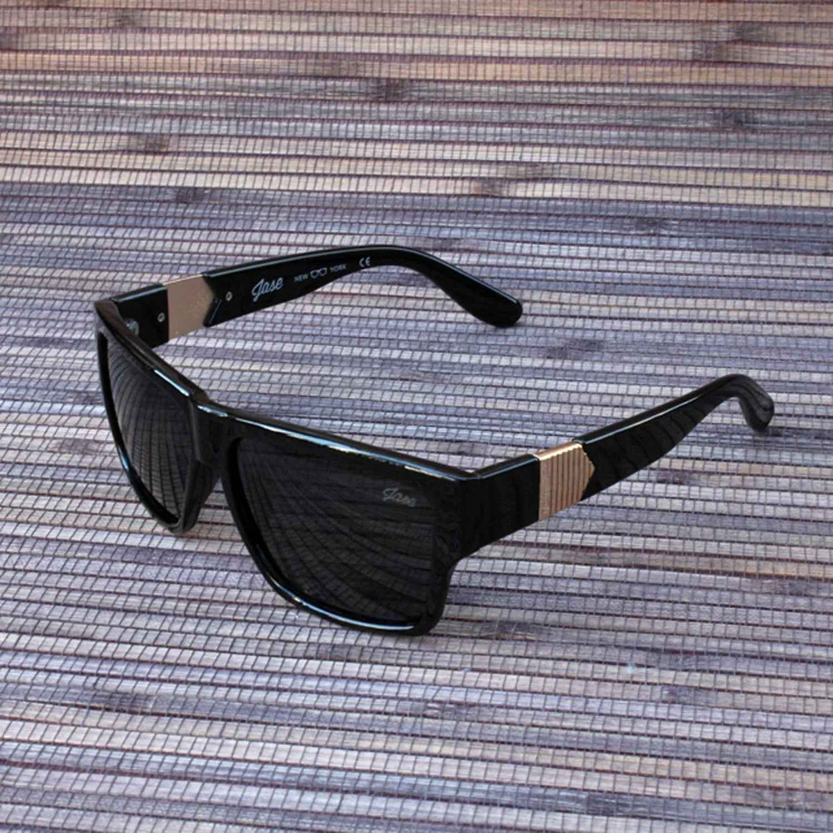 Black square-framed Jase New York Carter sunglasses angled to show temple arms and pyramid detail.