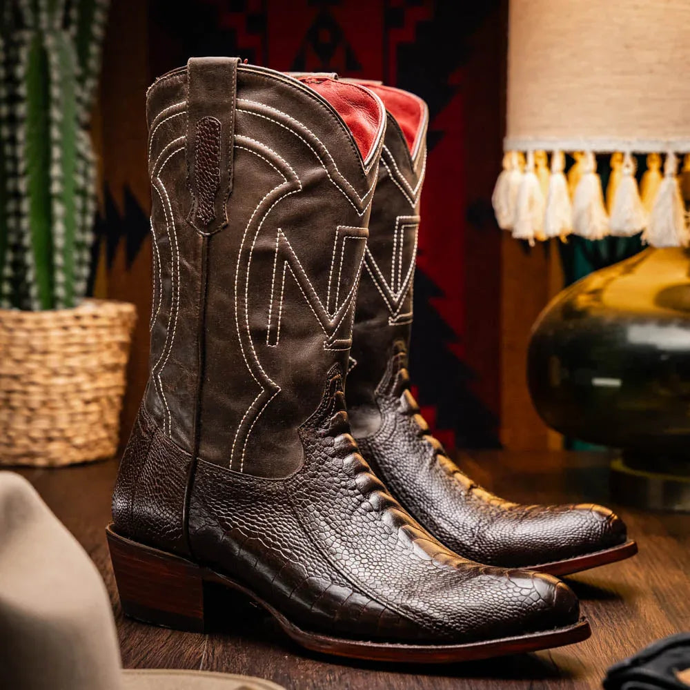 Lifestyle shot of a person wearing Denver ostrich leather cowboy boots with jeans outdoors.