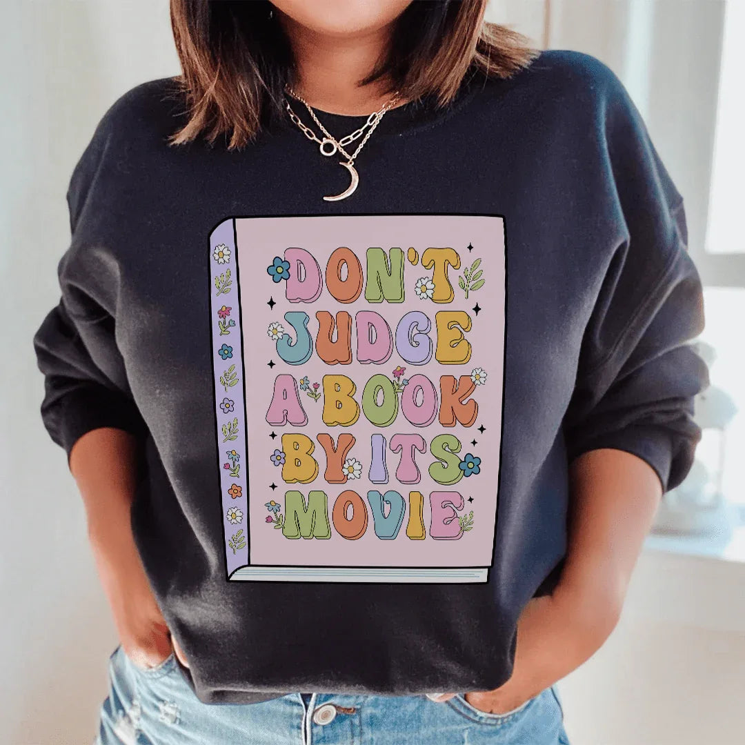 Black 'Don't Judge A Book' sweatshirt with peachy pink text, size small, soft cotton/poly fleece blend.