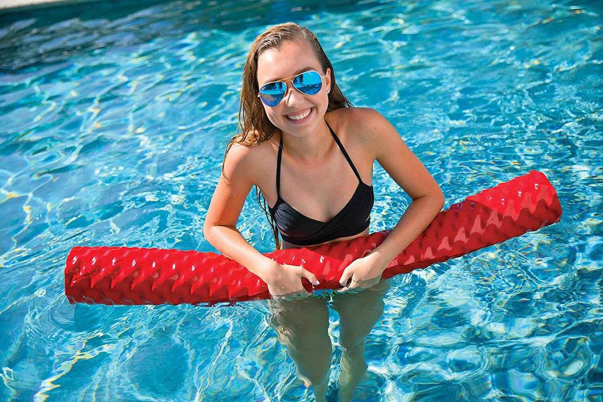 Red foam pool noodle floating on water, demonstrating buoyancy and size