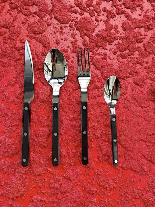 Close-up of modern ivory-handled forks and spoons from the Nordic flatware set resting on a textured fabric.