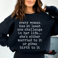 Close-up of black sweatshirt fabric showing white text 'Every Woman Has At Least One Challenge In Life'.