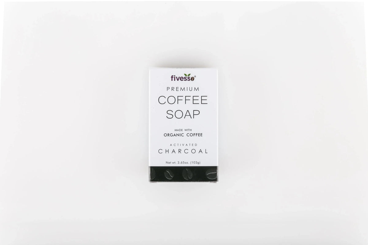 Activated charcoal coffee soap bar on a beige cloth with coffee beans and a rustic natural background.