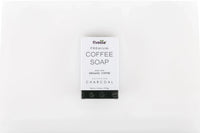 Activated charcoal coffee soap bar on a beige cloth with coffee beans and a rustic natural background.