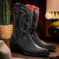 Lifestyle image of person wearing Georgia black stingray cowboy boots with jeans outdoors.