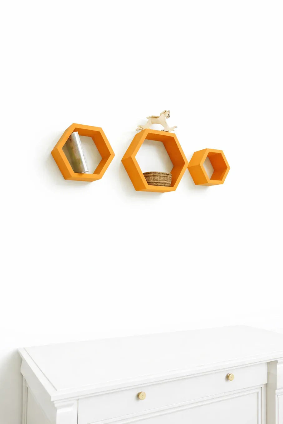 Set of 3 orange hexagon wall shelves mounted on white wall with decorative items