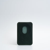 Green top-grain leather MagSafe wallet for iPhone on white background, highlighting smooth texture.