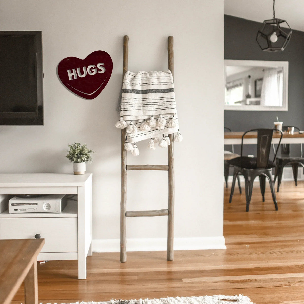 Hugs Candy Heart metal wall art displayed beside a wooden ladder against white wall