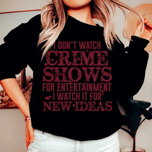Black sweatshirt with white text saying 'I Don't Watch Crime Shows For Entertainment', displayed flat on light background.