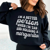 Black T-shirt front view displaying text 'I'm A Better Person When I'm Tan And Holding A Margarita' in peach.