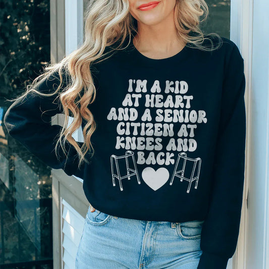 Black sweatshirt with 'I'm A Kid At Heart And A Senior Sitizen' text in white and peach fonts.