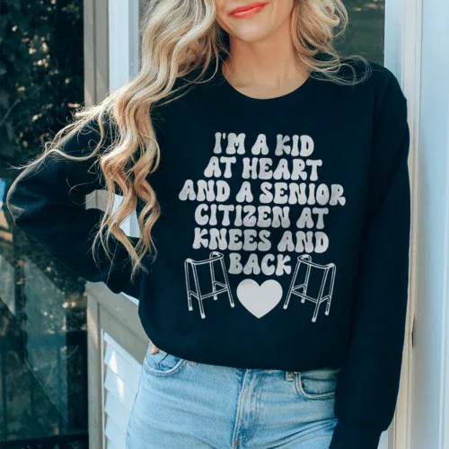 Black sweatshirt with white and peach lettering displaying 'I'm A Kid At Heart And A Senior Sitizen.'