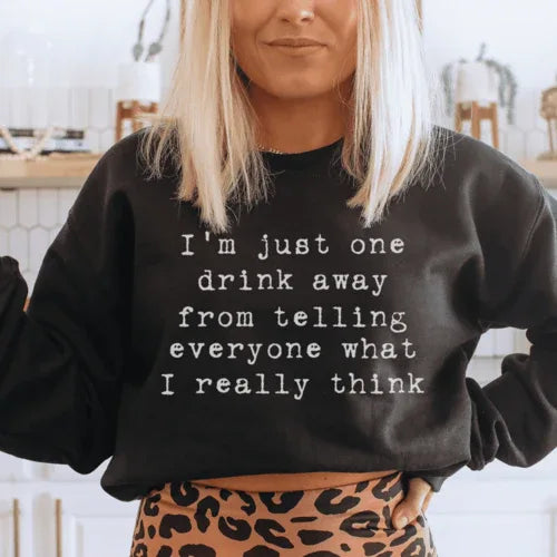 Close-up of peach sweatshirt showing fleece texture and 'I'm Just One Drink Away' printed text.