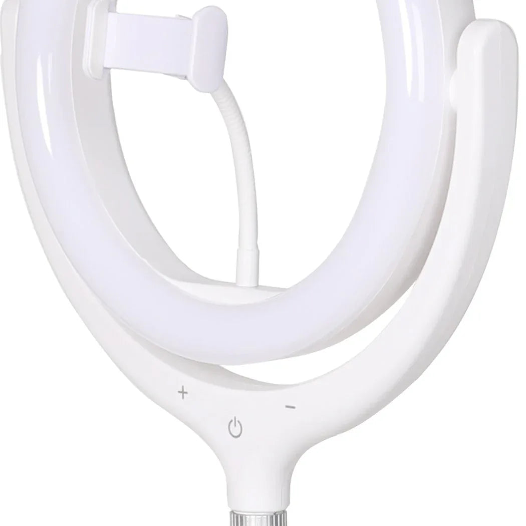 Woman using 12-inch LED ring light and phone holder tripod to take a selfie indoors.